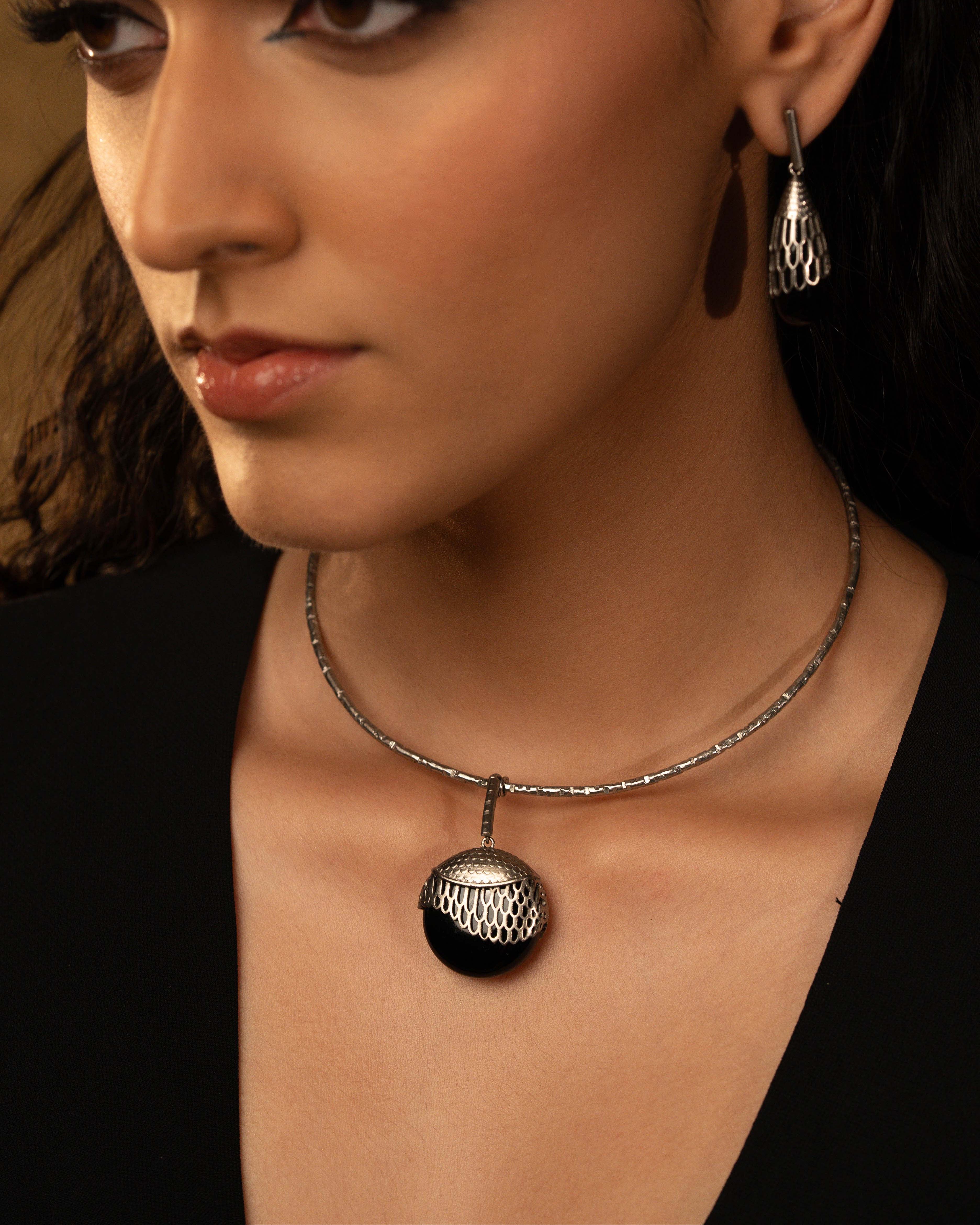 Close-up of a woman wearing a necklace with a pendant against a neutral background